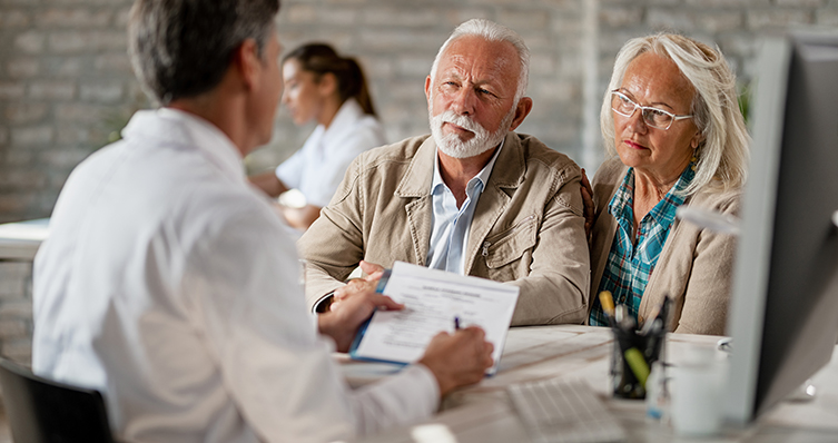 Senior couple consulting with healthcare worker about their insurance policy while having a meeting at clinic.